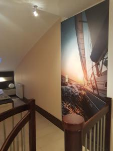 a room with a staircase with a painting of a boat on the wall at Apartament Baltic Marea in Międzyzdroje