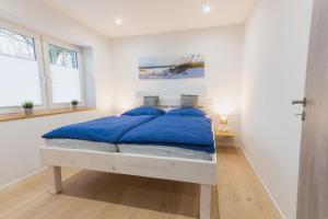 a white bedroom with a bed with blue pillows at Ferienwohnung Küstenurlaub Ueckermünde in Ueckermünde