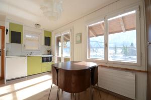 cocina con mesa de madera y 2 ventanas en The Boat House, en Goldswil