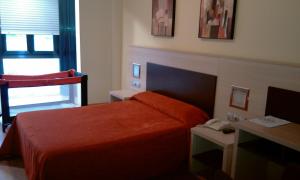 a bedroom with a bed and a desk with a phone at Hotel Avenida in Pontevedra