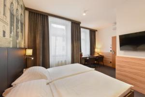 a hotel room with a white bed and a desk at Hotel Lucia in Vienna
