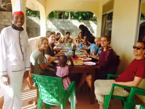 een groep mensen die rond een tafel zitten te eten bij Shimbwe Meadows Guest House in Moshi