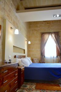 a bedroom with a blue bed and a window at Xemx in Qala