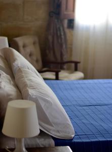 a bed with white pillows and a table with a lamp at Xemx in Qala