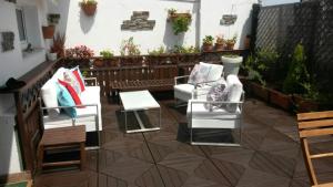 ヒホンにあるEl Atico de la Playaの白い椅子とテーブル、植物のあるパティオ