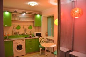 a kitchen with green cabinets and a table and a washing machine at Апартаменты Лето с ванной джакузи in Dnipro