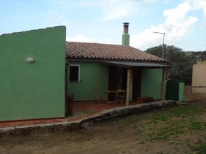 une maison verte avec une terrasse et une table dans l'établissement Casa Eleonora, à Santa Teresa Gallura