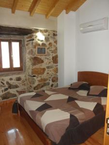 1 dormitorio con cama y pared de piedra en Casa Velha, en Figueiró dos Vinhos