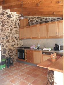 a kitchen with wooden cabinets and a stone wall at Casa Velha in Figueiró dos Vinhos