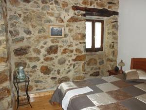 a bedroom with a stone wall with a bed and a window at Casa Velha in Figueiró dos Vinhos +18 photos