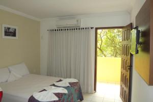 a bedroom with a bed and a sliding glass door at Sereia do Mar Pousada e Restaurante Ltda in Jacumã