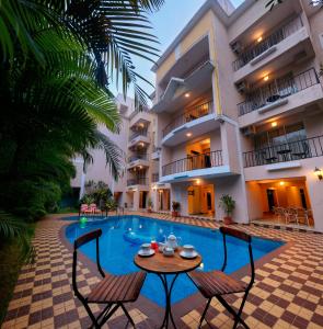 a swimming pool with a table and chairs in front of a building at TreeHouse Blue Hotel & Serviced Apartments in Majorda