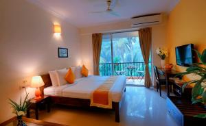 a bedroom with a bed and a television and a balcony at Treehouse Blue Hotel & Serviced Apartments in Majorda