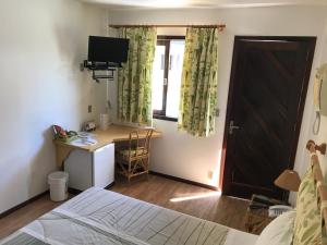 1 dormitorio con cama, escritorio y ventana en Hotel Bergblick, en Pomerode