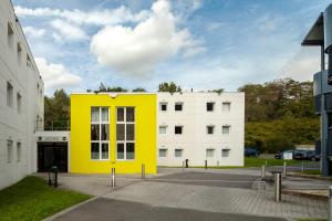 un bâtiment jaune devant un bâtiment blanc dans l'établissement B&B HOTEL Paris Nord Aulnay-sous-Bois, à Aulnay-sous-Bois