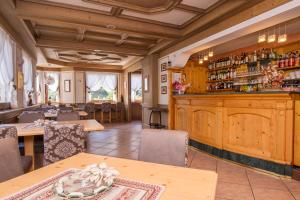 un restaurant avec un bar doté d'armoires et de tables en bois dans l'établissement Hotel Al Prato, à Fiera di Primiero