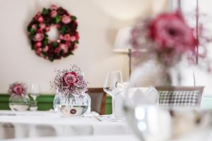 un tavolo con un vaso di vetro con dei fiori di Hotel Pienzenau Am Schlosspark a Merano