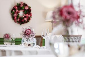 a table with a glass vase with flowers in it at Hotel Pienzenau Am Schlosspark in Merano