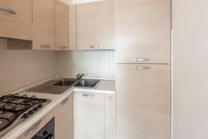 a kitchen with wooden cabinets and a sink at Residence Palazzo Mediterraneo in Tortoreto Lido