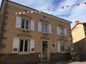 un edificio de ladrillo con ventanas blancas y banderas. en Auberge Des Petits en Saint-Igny-de-Vers