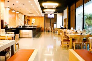 um restaurante com mesas e cadeiras de madeira e um bar em Wisdom Hotel & Residence em Rayong
