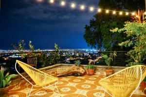 eine Terrasse mit Stühlen und Stadtblick in der Unterkunft Magic Garden House in Cali