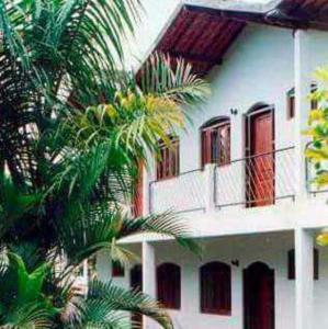a white building with a balcony and a palm tree at Excellence Apart in Ubatuba