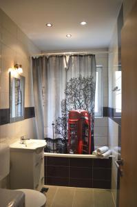 a bathroom with a red telephone booth in a shower curtain at Apartments Rubinić in Jelsa