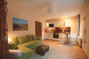 a living room with a green couch and a kitchen at Haus am Stadtturm Apartments in Traben-Trarbach