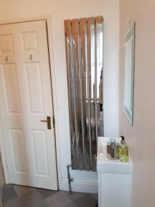 a bathroom with a door and a sink and a mirror at Green Gables Guest House in Windermere