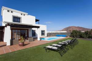 Casa blanca con sillas y piscina en Hipoclub Villas, Zafiro 34 en Playa Blanca