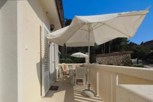 a white umbrella on a balcony with a table and chairs at Apartments Scheich in Šilo