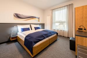 a bedroom with a bed with blue sheets and a window at Motel Grieskirchen superior in Grieskirchen