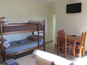 Habitación con litera, mesa y silla. en Cape Oasis Guesthouse, en Bloubergstrand