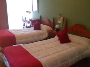 a bedroom with two beds with red and white sheets at Hotel Vazquez Diaz in Nerva