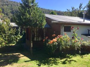 una casa con un árbol y flores en el patio en Tu Cabaña, en San Martín de los Andes