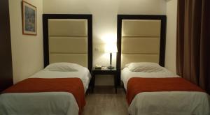 a hotel room with two beds and a table with a lamp at Castelli Hotel Nicosia in Nicosia