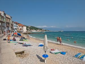 a beach with people on the water and an umbrella at Apartman Manuela in Baška