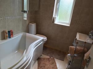 a bathroom with a tub and a toilet and a window at Wynchlands 4 Bedroom House in St Albans City in Saint Albans +36 photos
