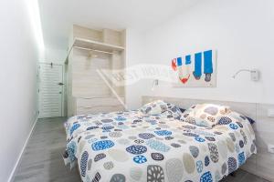 um quarto com uma cama com um edredão azul e branco em First line new apartment in Las Canteras em Las Palmas de Gran Canárias