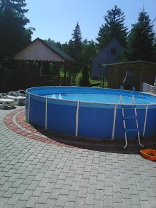 a large blue pool with a chair in a yard at Árvácska Nyaraló in Balatonmáriafürdő