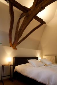 Schlafzimmer mit einem großen Bett mit Holzbalken in der Unterkunft B&B Het Agnetenklooster in Maaseik