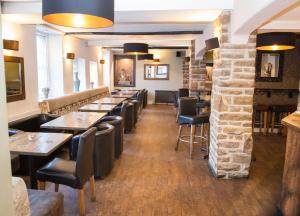 a restaurant with tables and chairs and a stone wall at The Manor House Hotel in Dronfield