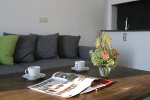 a coffee table with a vase of flowers and a magazine at GONIO Mgzavrebi III Apartment 403 in Gonio
