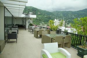 a balcony with tables and chairs and mountains in the background at GONIO Mgzavrebi III Apartment 403 in Gonio
