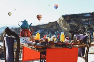 una mesa con comida y globos de aire caliente en el cielo en Asuwari Suites Cappadocia en Urgup