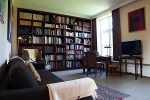 a living room with a couch and a television and book shelves at B&B Het Agnetenklooster in Maaseik