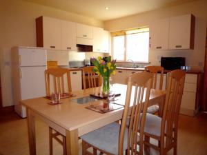 een keuken met een tafel met een vaas met bloemen erop bij Innisfallen Holiday Homes in Killarney