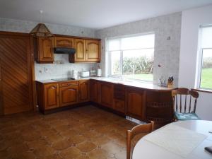 eine Küche mit Holzschränken, einem Tisch und einem Fenster in der Unterkunft El Martins in Miltown Malbay