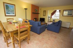 a living room with a wooden table and blue chairs at Willow Grove Holiday Homes No. 4 in Rosslare